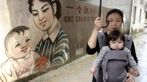 Die chinesische Filmemacherin Nanfu Wang, die heute in den USA lebt vor einer Propaganda-Schrift. Die Geburt ihres Sohns war Anlass für sie, sich mit der chinesischen Einkindpolitik auseinanderzusetzen.