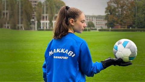 Ein Mädchen, das einen Fußball in der Hand hält.