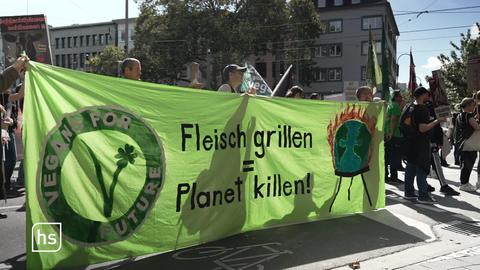 Veganer protestieren auf Straße mit Plakat.