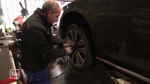 Mechaniker schraubt in Autowerkstatt Reifen an Auto.