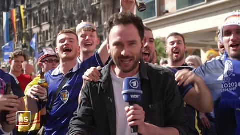 Reporter umringt von jubelnden Fußballfans