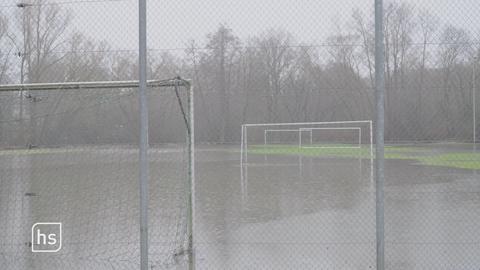 Regenwasser steht so hoch auf Fußballplatz, sodass kaum noch Rasen zu sehen ist.