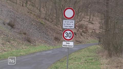 Kleine Straße im Wald mit Verkehrsschildern.