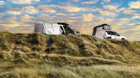 Wohnmobile und ein SUV mit Vorzelt stehen in den Dünen des Campingplatzes Vejers in Dänemark.