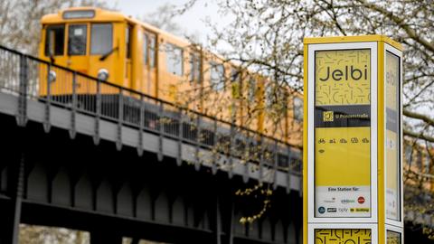 Eine U-Bahn fährt an dem Hinweisschild des Mobilitätshub Jelbi vorbei. Eine Auswahl von verschiedenen Sharing-Fahrzeugen unterschiedlicher Anbieter, vom Auto, über Fahrräder und Roller, stehen seit dem 12. April 2019 zur Nutzung bereit.