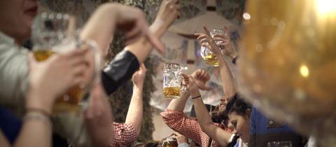 Oktoberfest: Menschen prosten sich mit Bierkrügen zu.