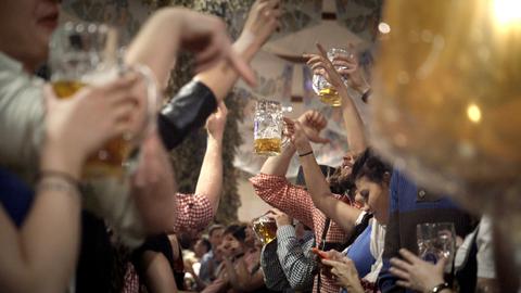 Oktoberfest: Menschen prosten sich mit Bierkrügen zu.