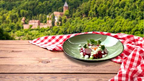 Ein Gericht aus der Sendung auf einem Tisch, im Hintergrund die Burg Zwingenberg