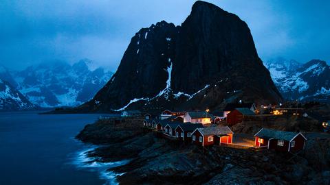 Beleuchtete Häuser auf einer Insel in den Lofoten in der Abenddämmerung.