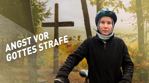 Eine Frau mit Fahrradhelm blickt ernst in die Kamera, im Hintergrund sieht man ein Kreuz.