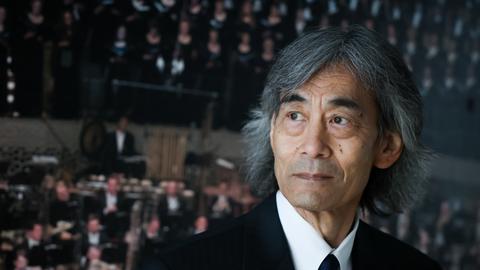 Kent Nagano, Generalmusikdirektor der Hamburger Staatsoper und Chefdirigent des Philharmonischen Staatsorchesters Hamburg, steht vor einem Poster eines Konzerts aus der Elbphilharmonie am Rande einer Veranstaltung im Musikkindergarten Finkenau.