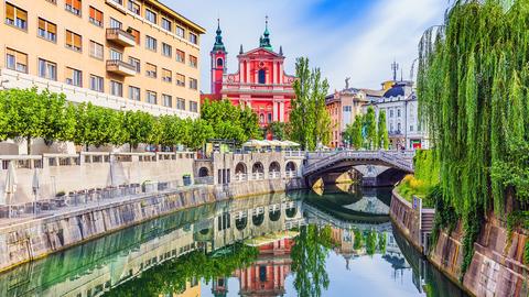 Sommerlicher Blick auf Kanal und bunte Häuser in Ljubljana.