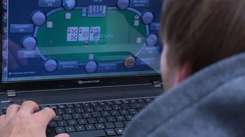 Ein Mann spielt an seinem Laptop ein Online-Pokerspiel.