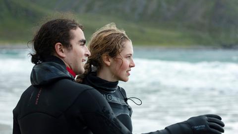 Lukas (Marlon Valdés Langeland) nimmt Karin (Mathilde Holtedahl Cuhra) zum Surfen mit – trotz des gefährlichen Wellengangs.