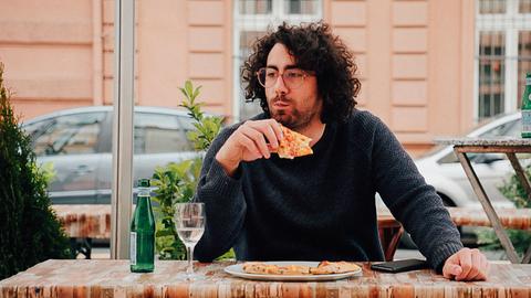 Reporter Davide Di Dio beißt in ein Stück Pizza. 