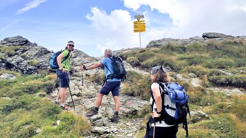 Drei Personen überqueren die Alpen.