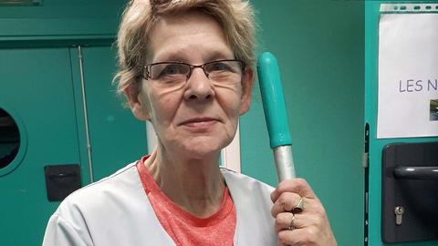 Putzfrau mit Wischmob in der Hand schaut traurig in die Kamera. 