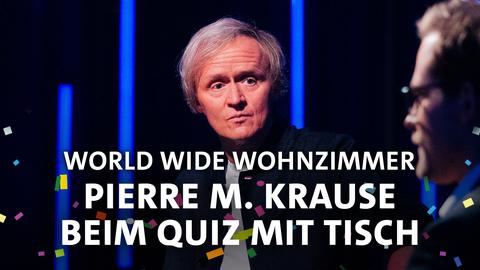 Pierre M. Krause schaut sehr skeptisch. Text: World Wide Wohnzimmer - Pierre M. Krause beim Quiz mit Tisch