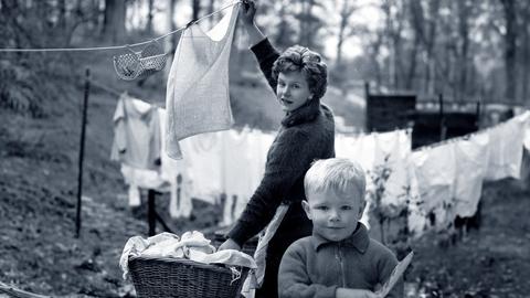 Zwischen Romantik und Windelwaschen der 60er: Hausfrau mit kleinem Kind beim Wäsche aufhängen. 