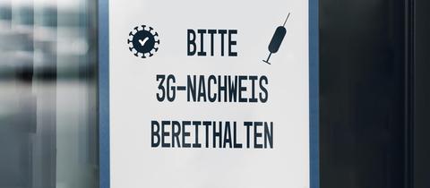 Schild vor einem Arbeitsplatz: Liebe Mitarbeiter, bitte 3G-Nachweis bereithalten.
