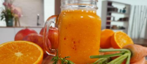 Glas mit warmem Vitamin Smoothie und Orangen-, Karottendeko