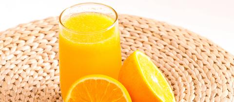 Orangensaft im Glas mit Orangenhälften