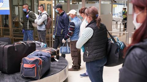 Menschen warten am Gepäckband auf ihr Gepäck