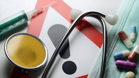Symbolfoto medizinischer Behandlungsfehler: Stethoskop, Spritze, Tabletten und Warnschild