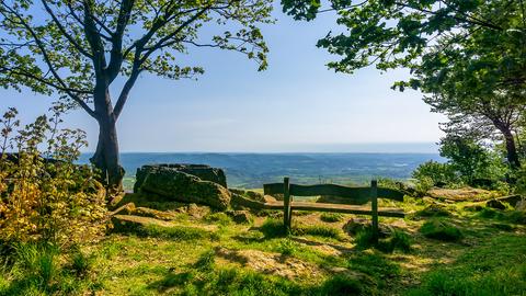 Einsame Holzbank auf einem Berg mit Blick über eine Landschaft.
