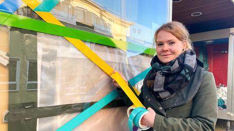 Katrin Hitziggrad steht mit Klebeband vor einem leeren Laden in der Innenstadt.