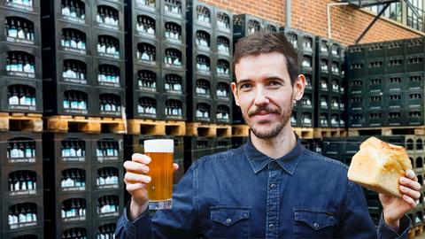Gründer Daniel Anthes hält Bier und Brot in der Hand, dahinter Bierkisten.