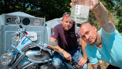 Friso sitzt auf Motorrad, rechts vorne Protagonist, der Flasche auskippt. 