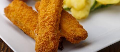 Fischstäbchen mit Kartoffelsalat auf dem Teller 