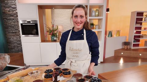 Konditormeisterin Theresa Mendel im hallo hessen-Studio mit vielen Heidelbeer-Tartelettes.