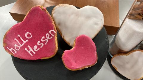 Amerikaner in Herzform mit rosa Zuckerguss verziert und Schrift "hallo hessen"
