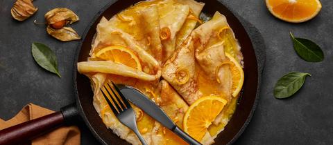 Eine Pfanne mit Crepes und Orangenscheiben