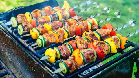 Mehrere Spieße mit Fleisch und Gemüse auf einem Grill.
