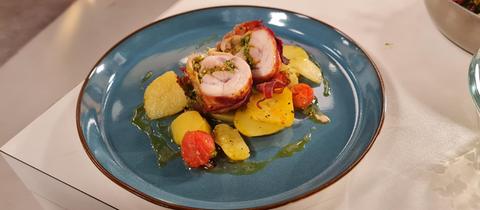 Hähnchen-Spieße im Schinkenmantel auf Kartoffeln mit Tomaten, angerichtet