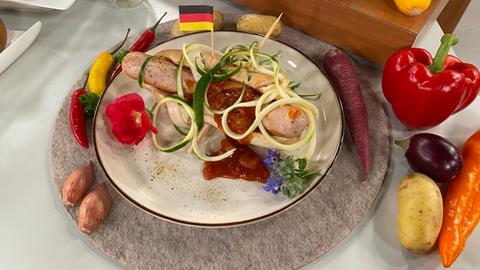 Vogelsberger Hot-Dog mit herzhafter Kohlrabi-Apfelsoße auf einem Teller serviert.