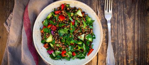 Eine Schüssel veganer Linsensalat mit Gurken, Paprika und Petersilie