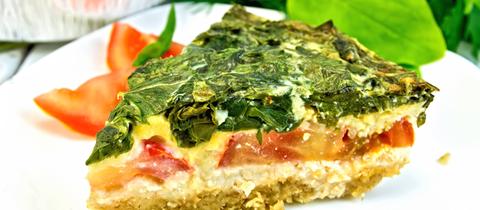 Gemüsekuchen auf einem Teller, angerichtet mit Tomaten. 