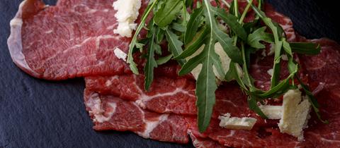 Frisches Carpaccio mit Rucola auf Schiefer.