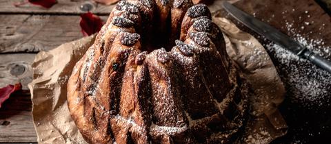 Gugelhupf auf verwitterter Holztischplatte in der Nähe von trockenem Herbstlaub