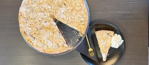 Ein Kirsch-Streusel-Kuchen von dem ein Stück abgeschnitten wurde