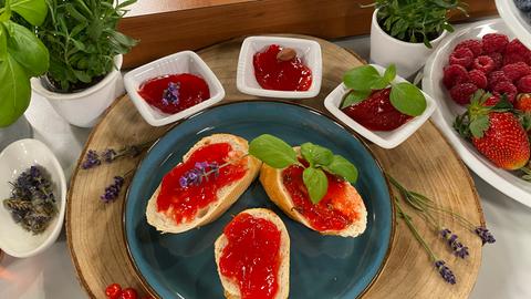 Erdbeermarmelade auf Brotscheiben mit Beeren und Kräutern