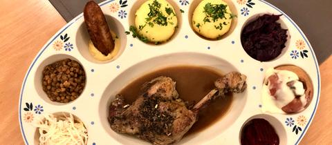 Das "Neinerlaa" auf einem Portionierteller. Neun verschiedene kleine Speisen nebeneinander.