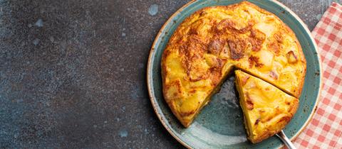 Hausgemachte Tarte Tatin-Torte mit Kartoffeln, Käse, Knoblauch, schwarzem und rosa Pfeffer auf dunklem, strukturiertem Hintergrund, Nahaufnahme, selektiver Fokus.