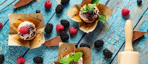 Vegane Blaubeer-, Himbeer- und Brombeermuffins mit Schokolade und einem Nudelholz.