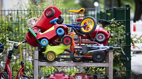 Bobby-Cars, andere Spielautos und Gefährte für Kinder liegen angeschlossen vor einer Kita.