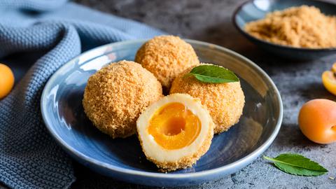 Angeschnittenee Marillenknödel auf einem blauen Teller.